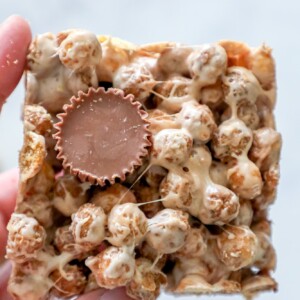 A hand holding a piece of Reeses popcorn.
