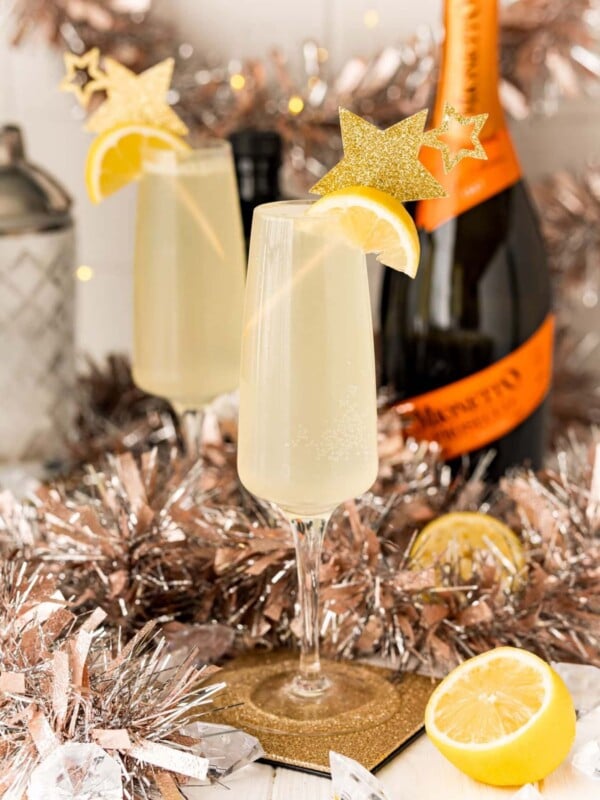 Two glasses of champagne with lemon slices and tinsel in a festive cocktail story.