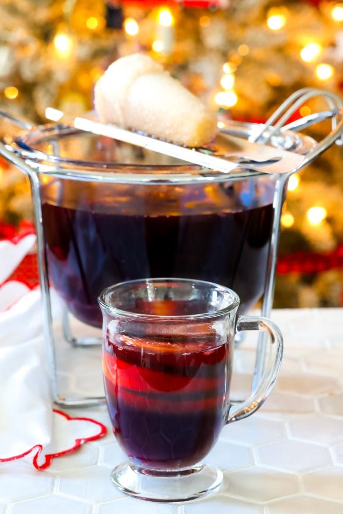 mug with rum punch in front of flaming punch bowl and sugar on fire on top of it