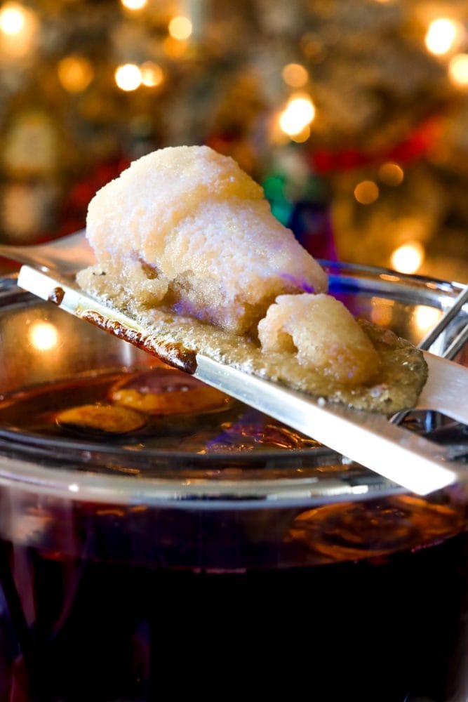 mug with rum punch in front of flaming punch bowl and sugar on fire on top of it