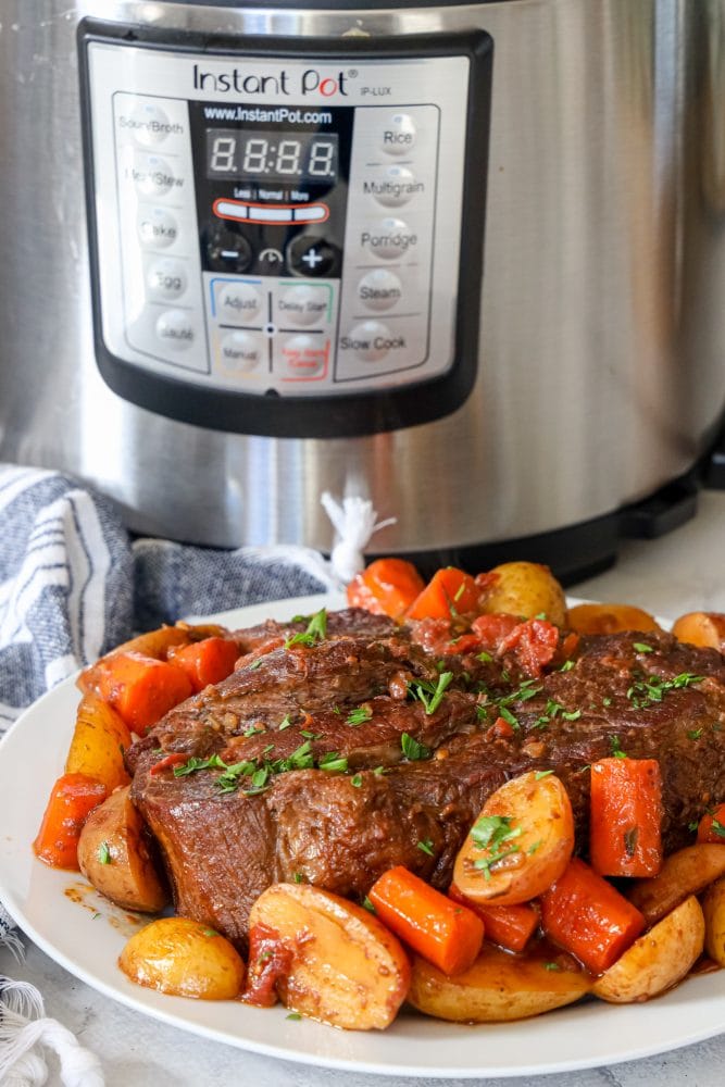  pot roast and vegetables on a plate in front of an instant pot