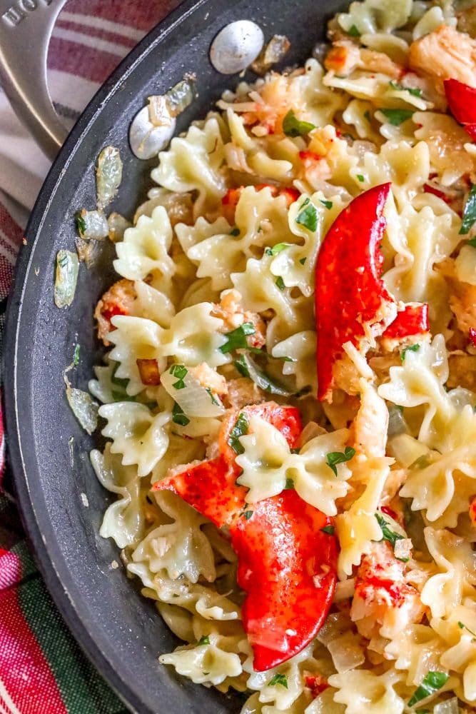 bowtie pasta in a pan with herbs, cheese, sauteed onions, and lobster meat