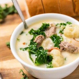 A keto zuppa toscana recipe with meat and kale displayed on a cutting board.