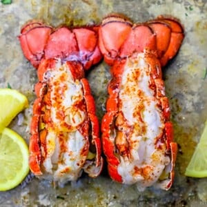 picture of broiled lobster tails on a baking sheet with lemon slices next to them
