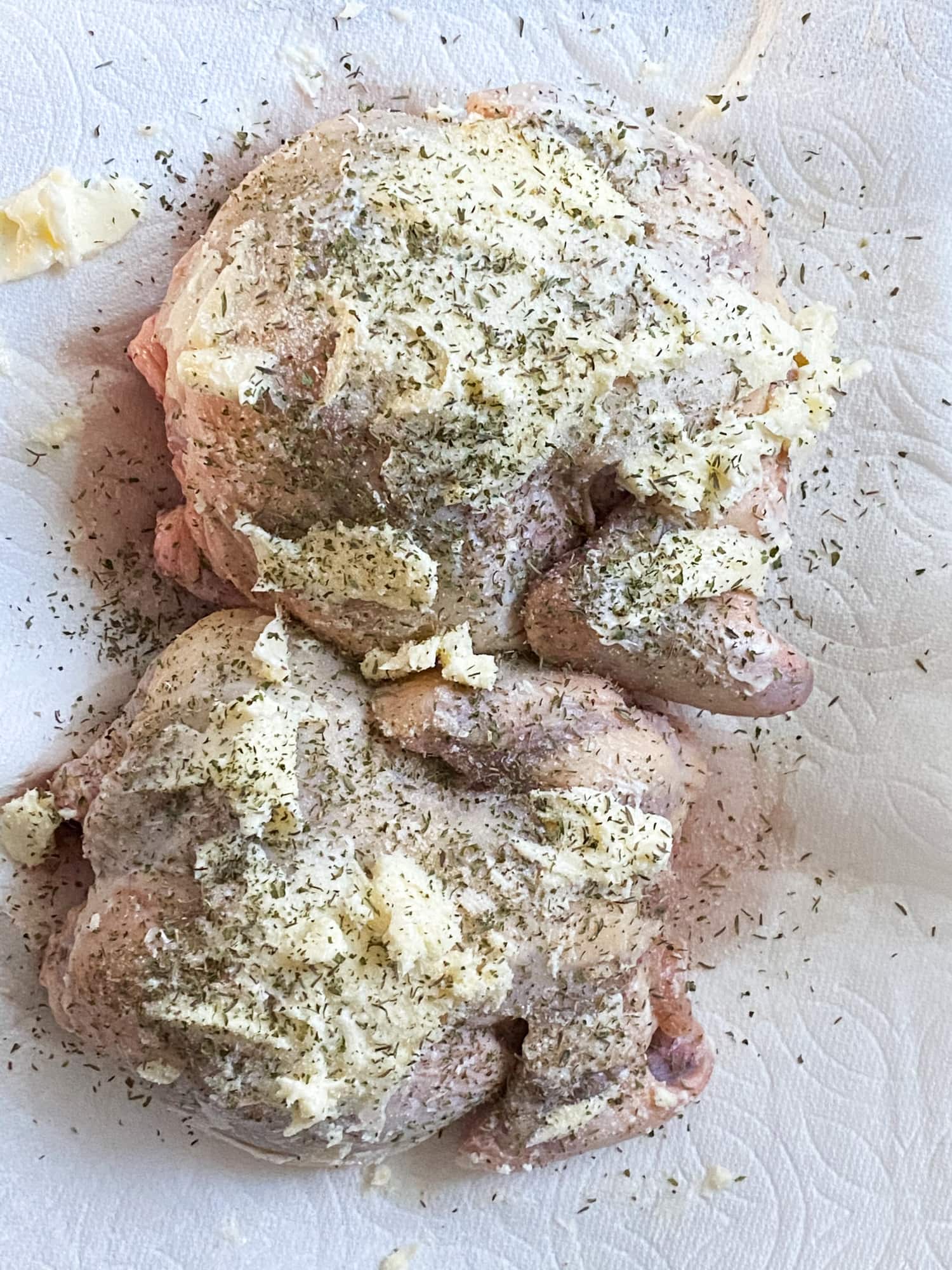 raw chicken with butter and spices on it