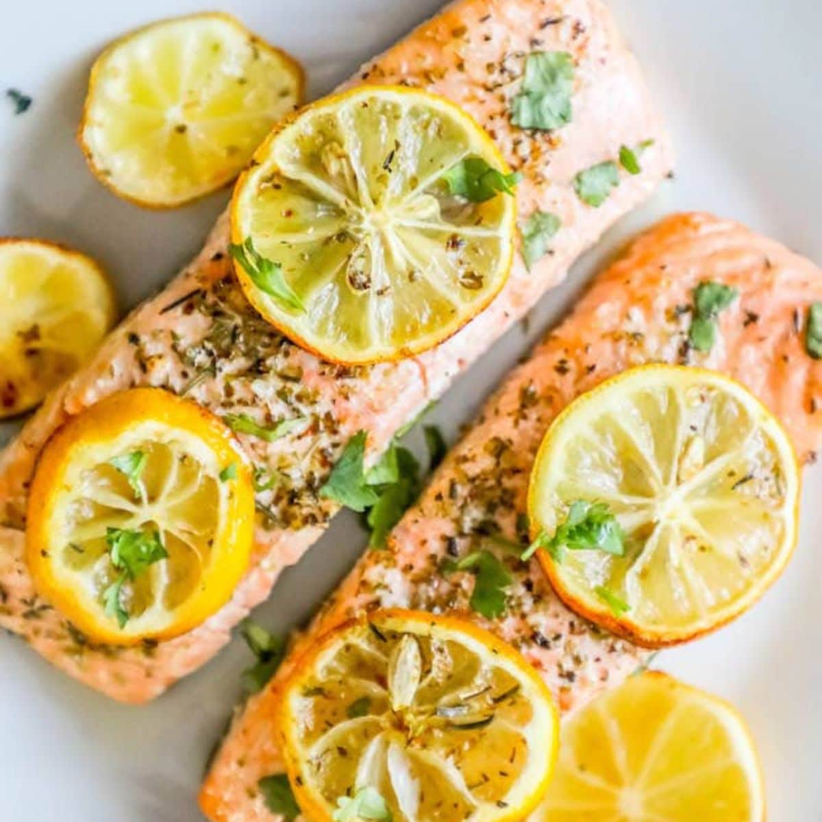 salmon filets on a white plate with lemon slices