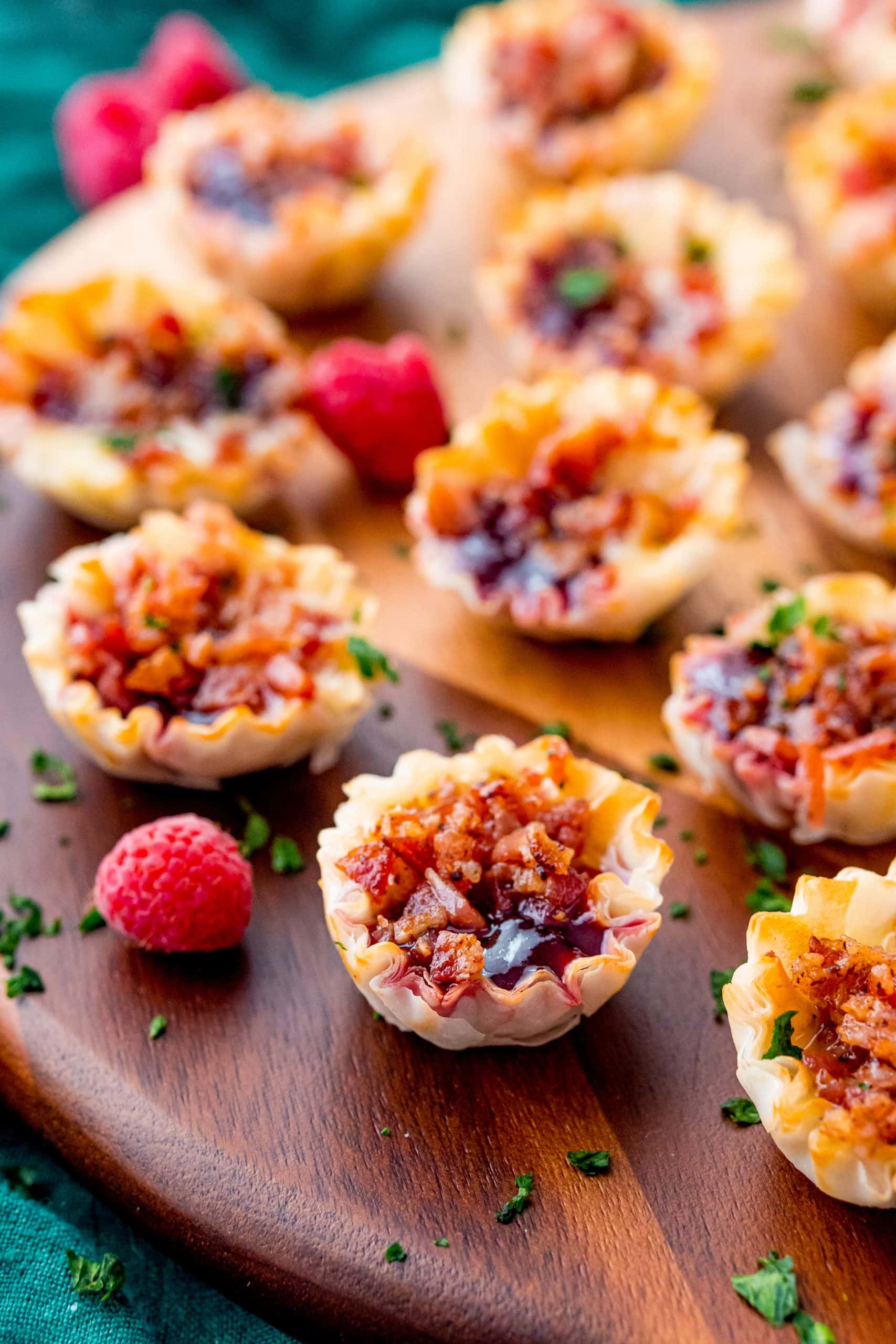 Mini tarts filled with raspberry jam, creamy cheese, and crispy bacon bits, a perfect sweet and savory bite.