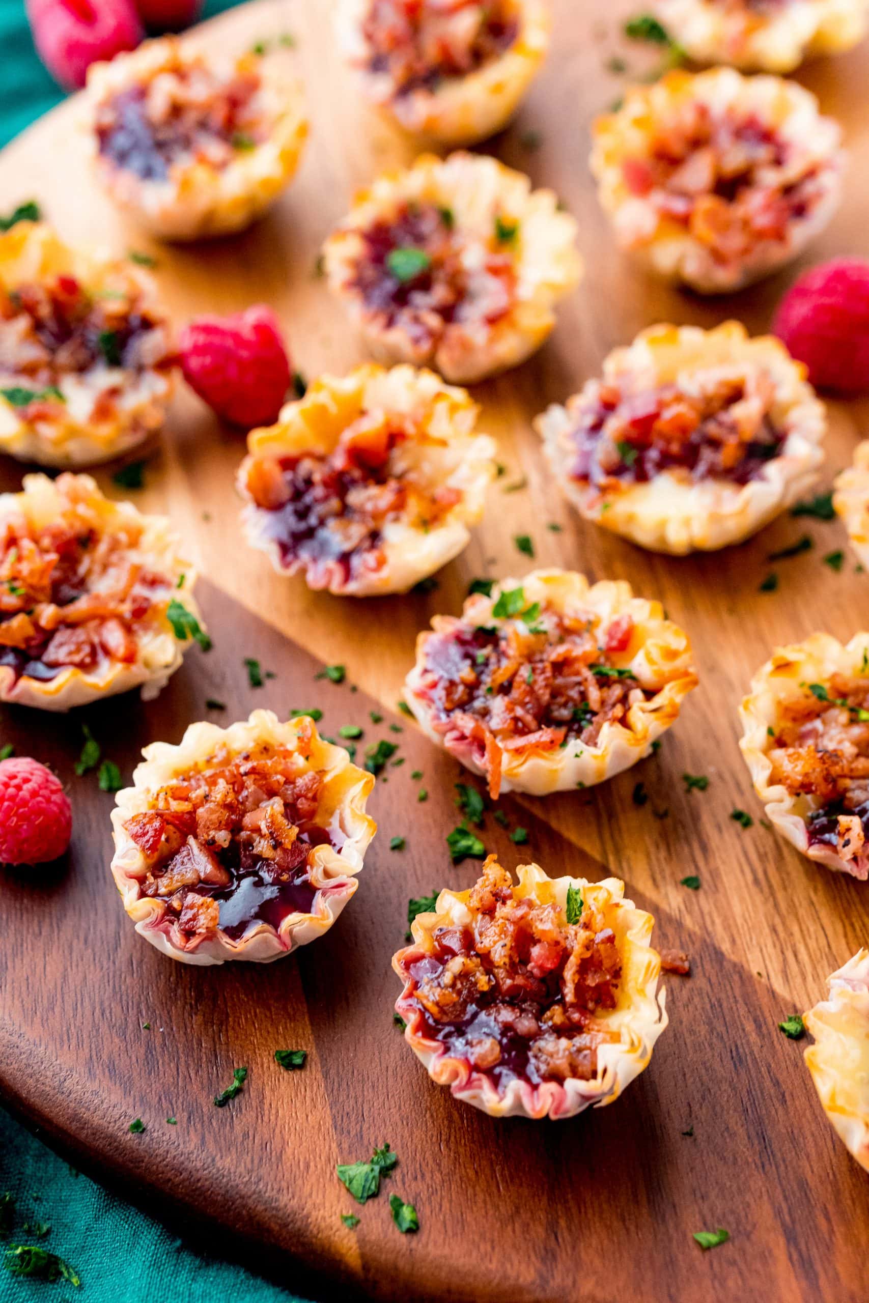 A selection of raspberry and bacon bites arranged on a rustic cutting board, highlighting their vibrant colors and textures.