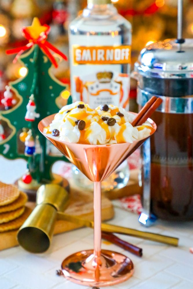 brass martini glass with cream, espresso beans, and cinnamon stick sticking out