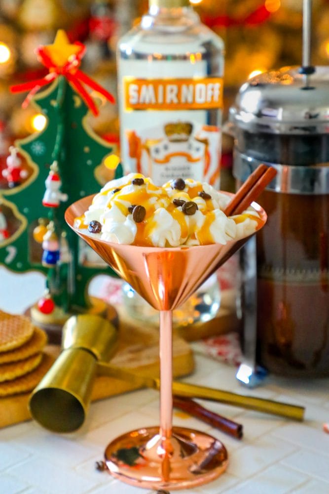 brass martini glass with cream, espresso beans, and cinnamon stick sticking out