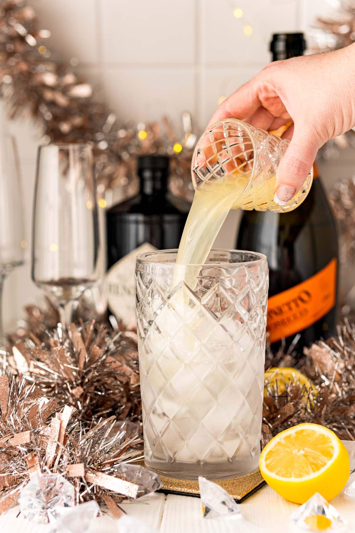 A person pouring a Champagne gin cocktail into a glass.