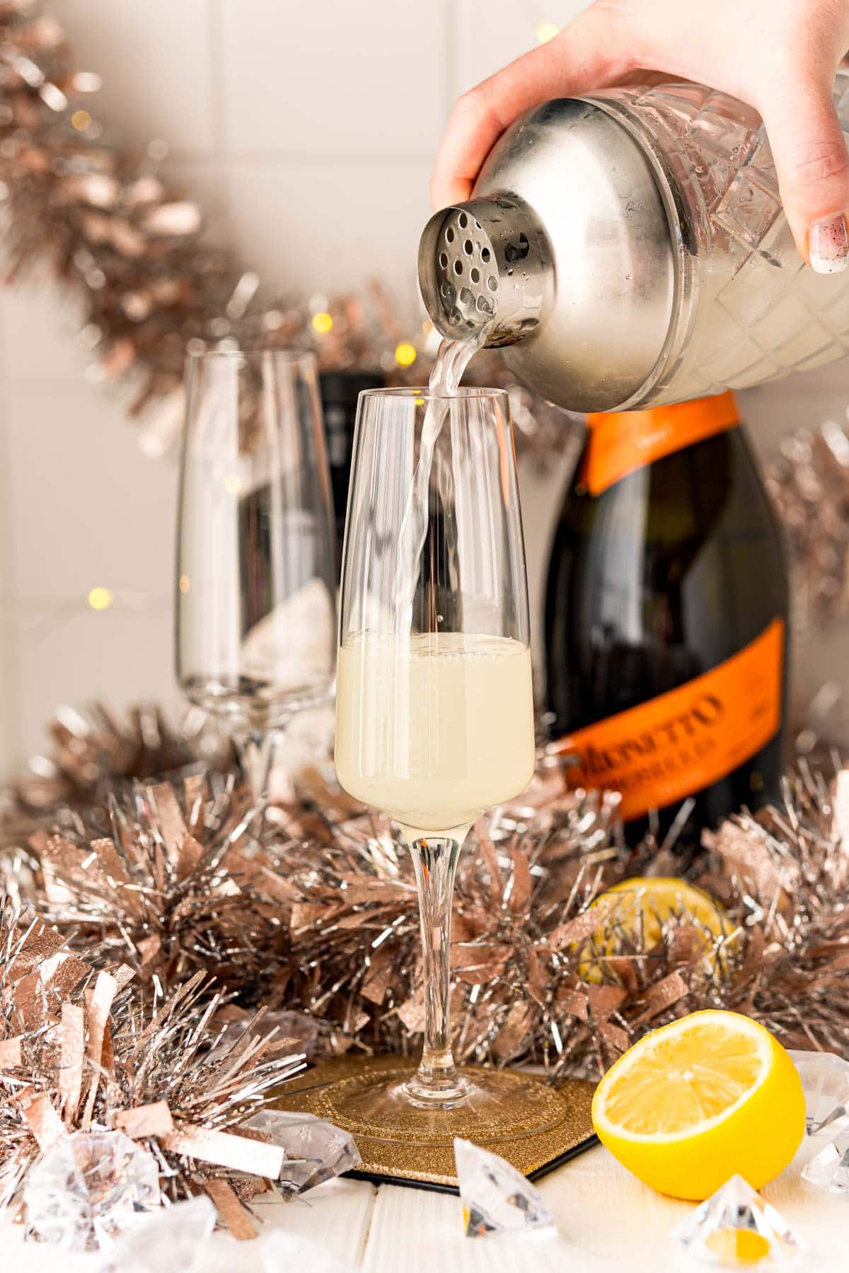 A person pouring a Champagne Gin Fizz cocktail.