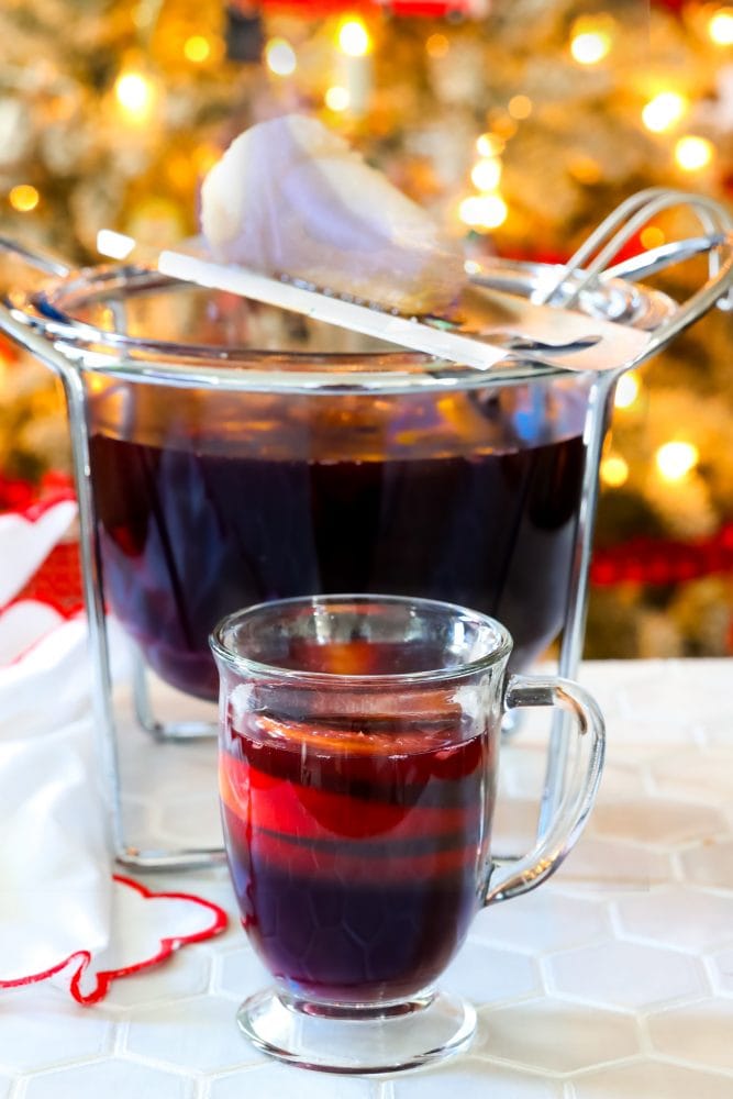 mug with rum punch in front of flaming punch bowl and sugar on fire on top of it