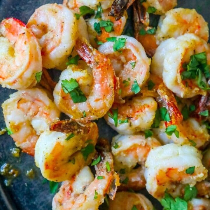 air fried shrimp on a plate covered in parmesan and garlic with chopped parsley