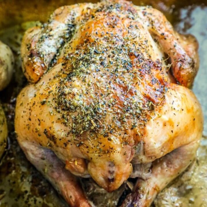 roasted cornish game hen on a baking sheet with herbs, garlic, and butter