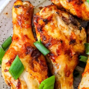 Chicken wings with piri piri seasoning served on a white plate garnished with green onions.