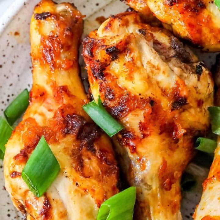 Chicken wings with piri piri seasoning served on a white plate garnished with green onions.