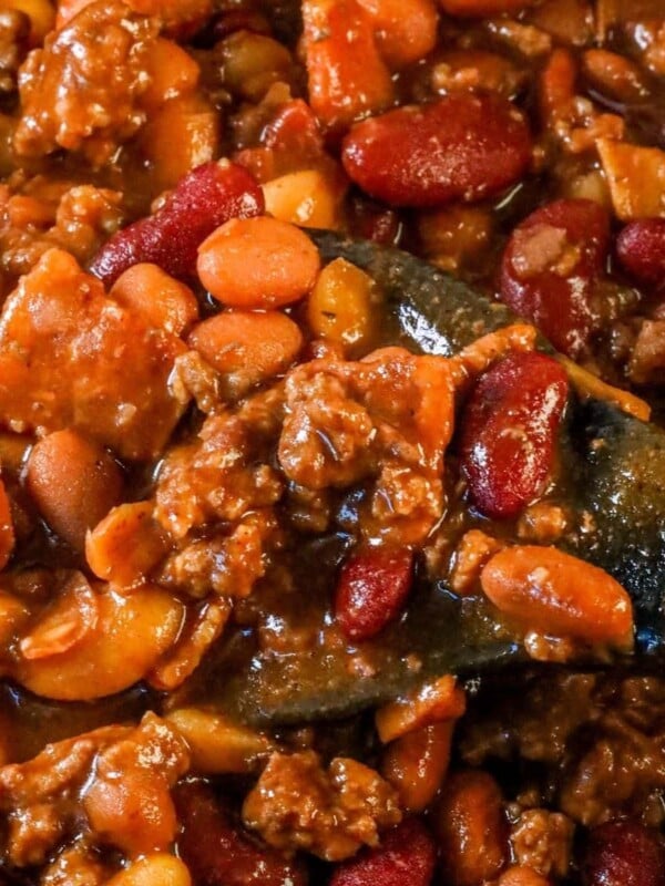 A bowl of the best ever slow cooker bean bake, served with a wooden spoon.
