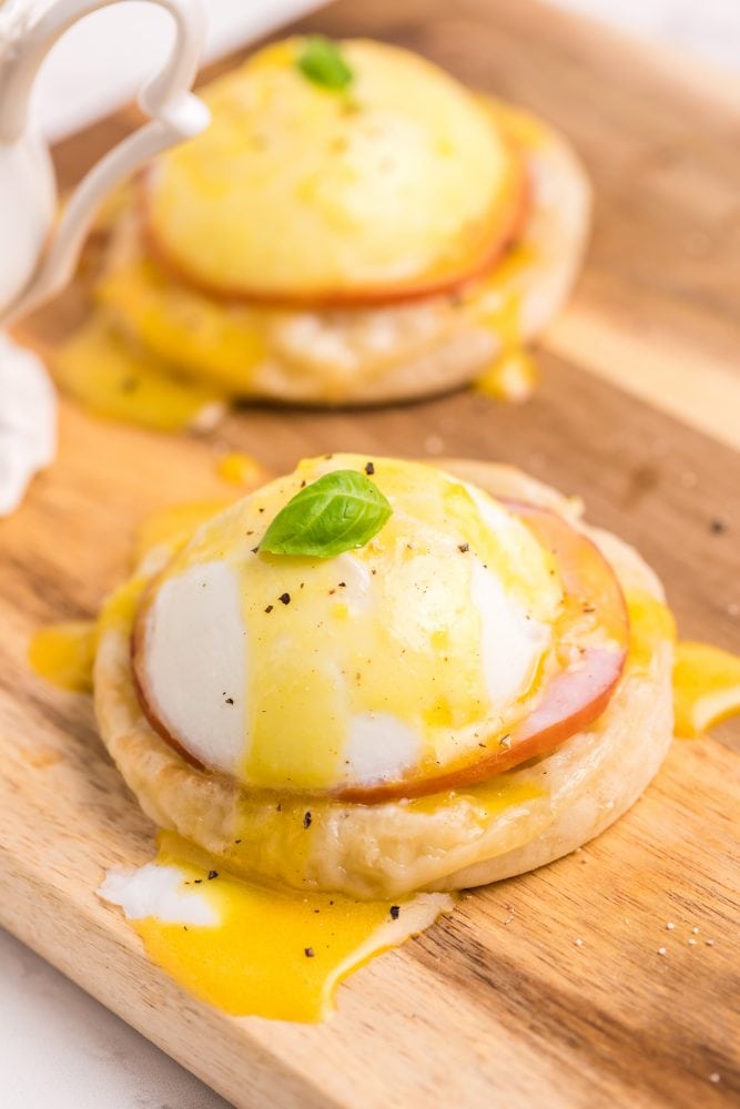 English muffin with a piece of Canadian bacon, a poached egg, and hollandaise sauce on it, egg yoke is running