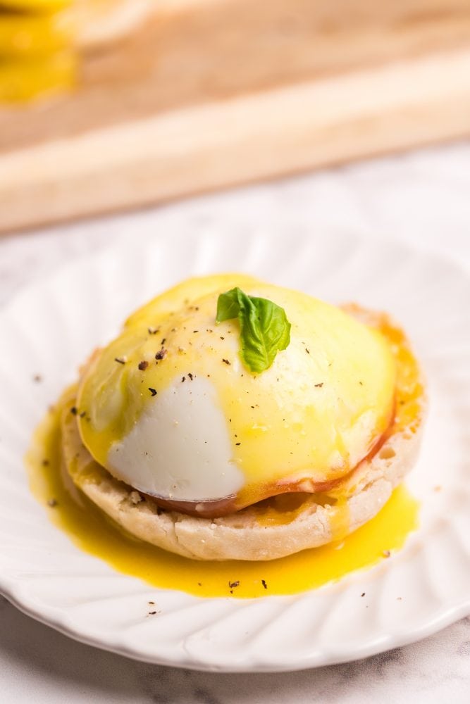 English muffin with a piece of Canadian bacon, a poached egg, and hollandaise sauce on it