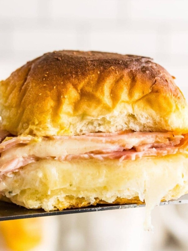 A baked ham and cheese sandwich being held up by a fork.