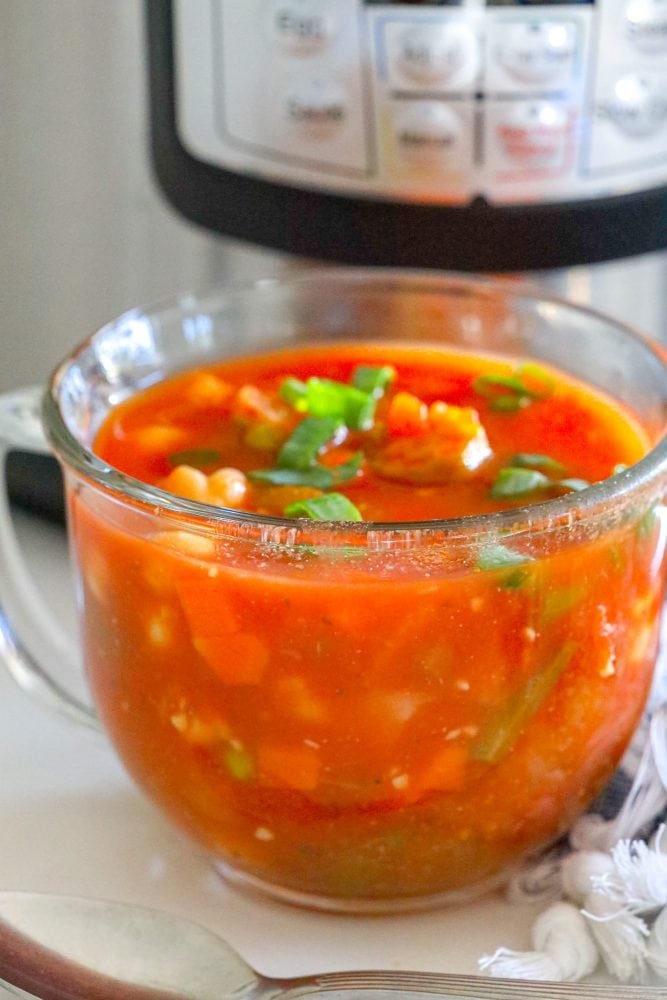 vegetable soup in a mug in front of an instant pot