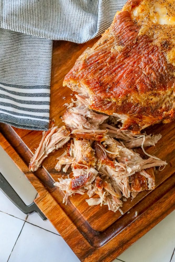 pulled pork with crunchy skin shredded on a cutting board