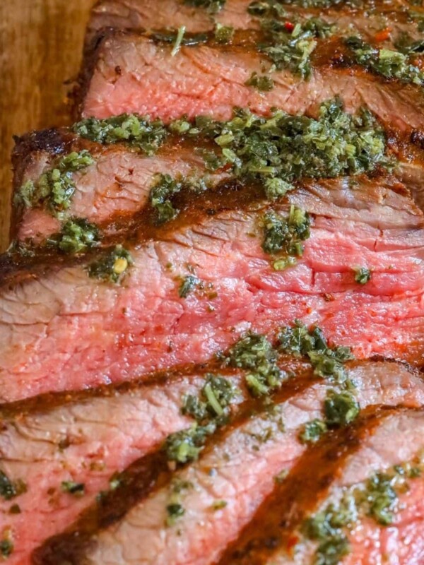 picture of sliced tri tip steak on a cutting board with chimichurri sauce on top
