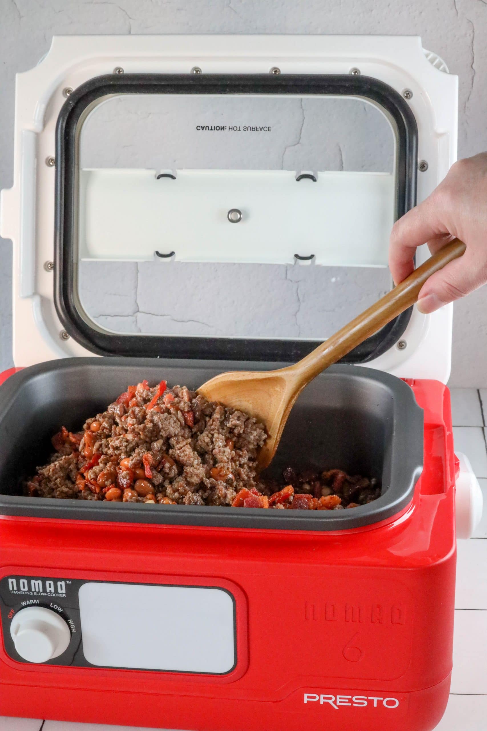 A person is preparing the best ever bean bake recipe using a presto slow cooker.