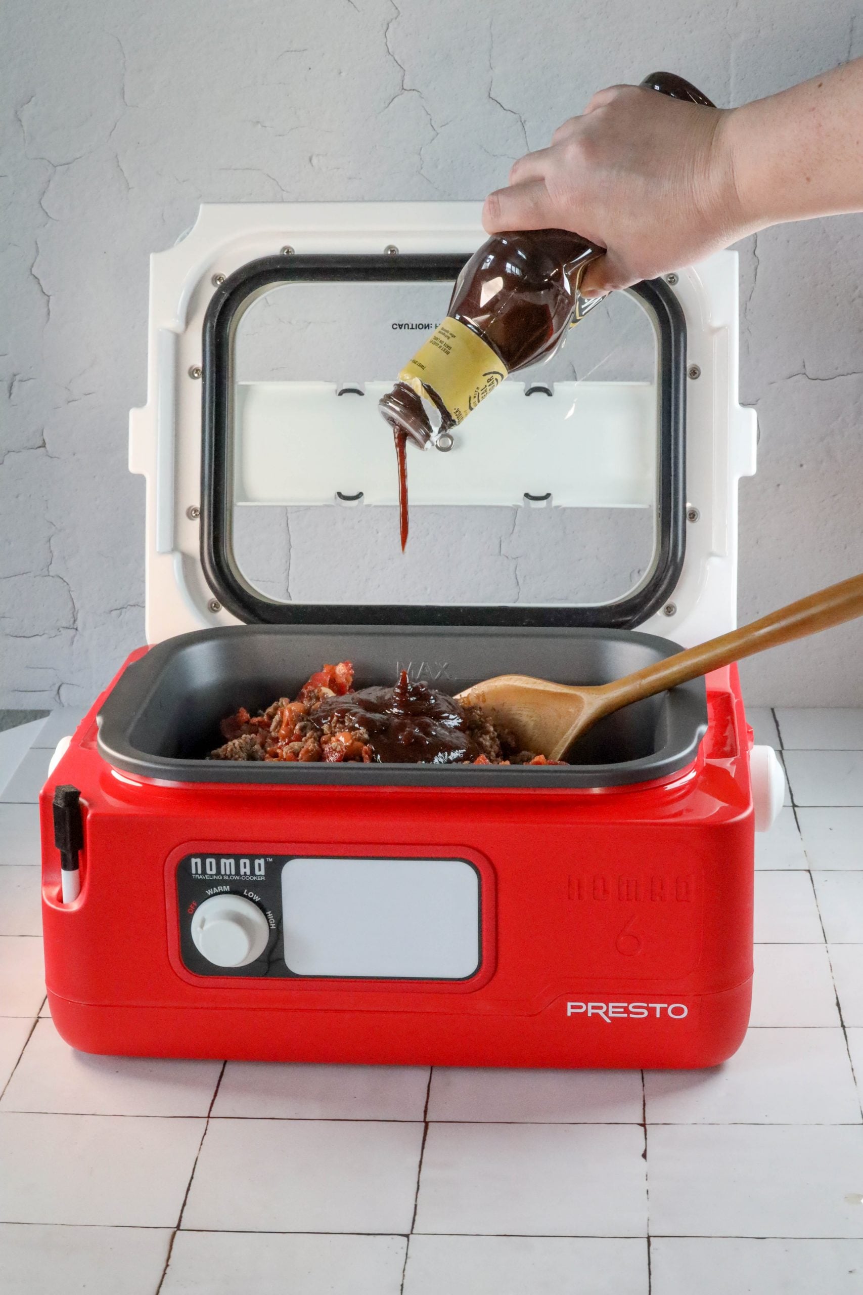 A person effortlessly pours sauce into a red microwave oven while following an easy bean bake recipe.