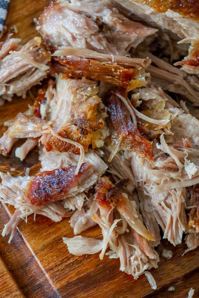 picture of pulled pork with crunchy skin shredded on a cutting board