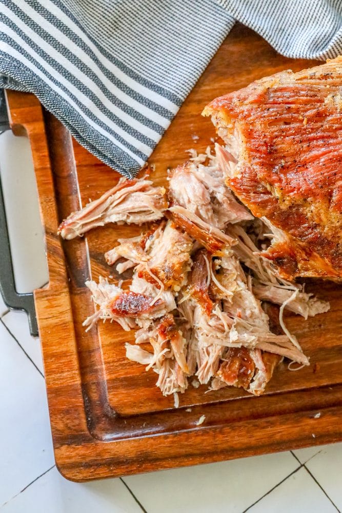 pulled pork with crunchy skin shredded on a cutting board