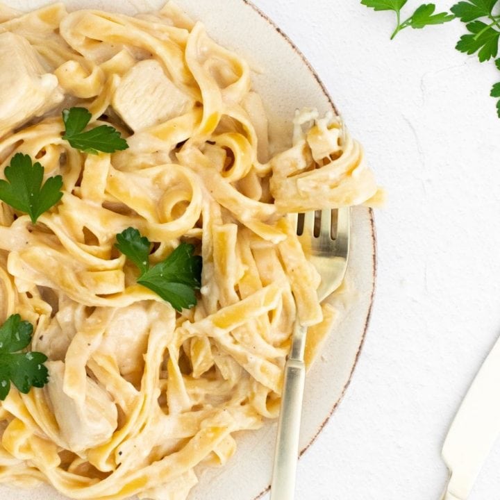 Instant Pot chicken alfredo with parsley served on a white plate.