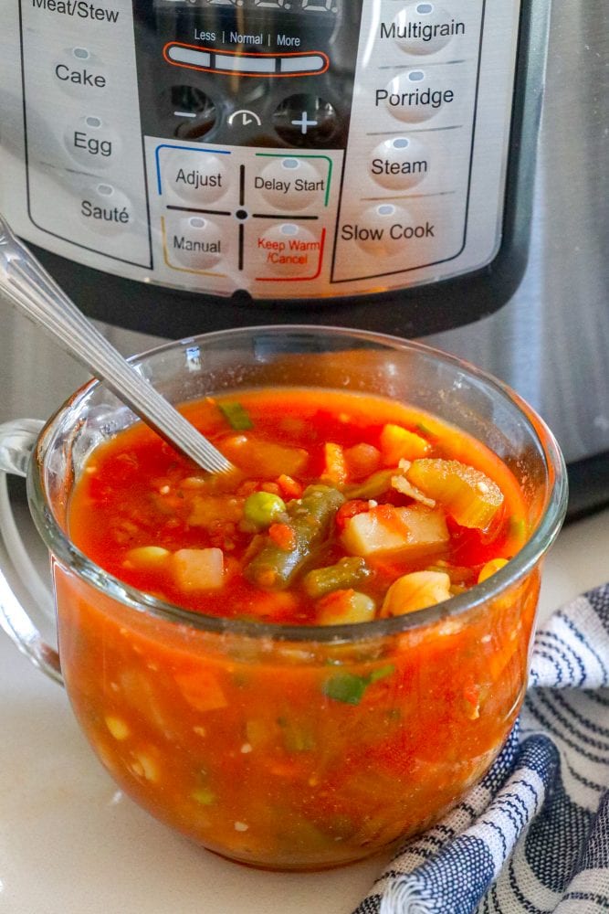 tomato and vegetable soup in a clear mug in front of an instant pot