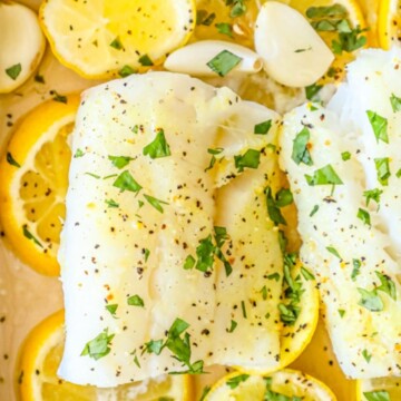 picture of baked cod in a dish with lemon and garlic cloves