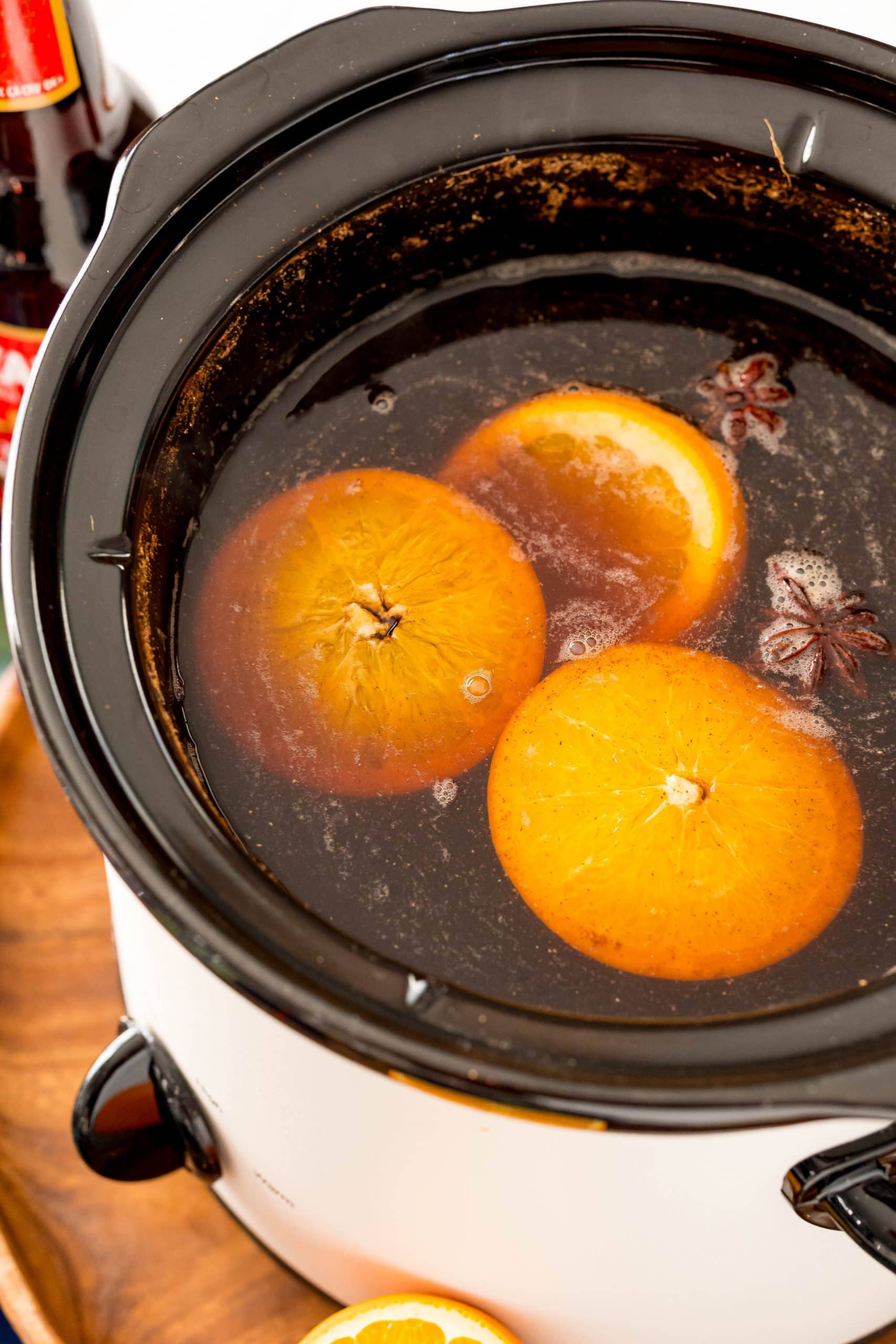 An easy mulled beer recipe made with a crock pot filled with orange slices and a bottle of beer.