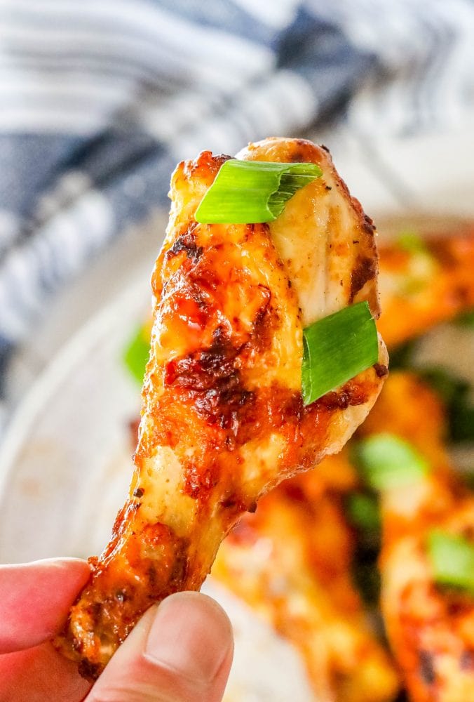 picture of spiced chicken drumsticks with green onions on it. 