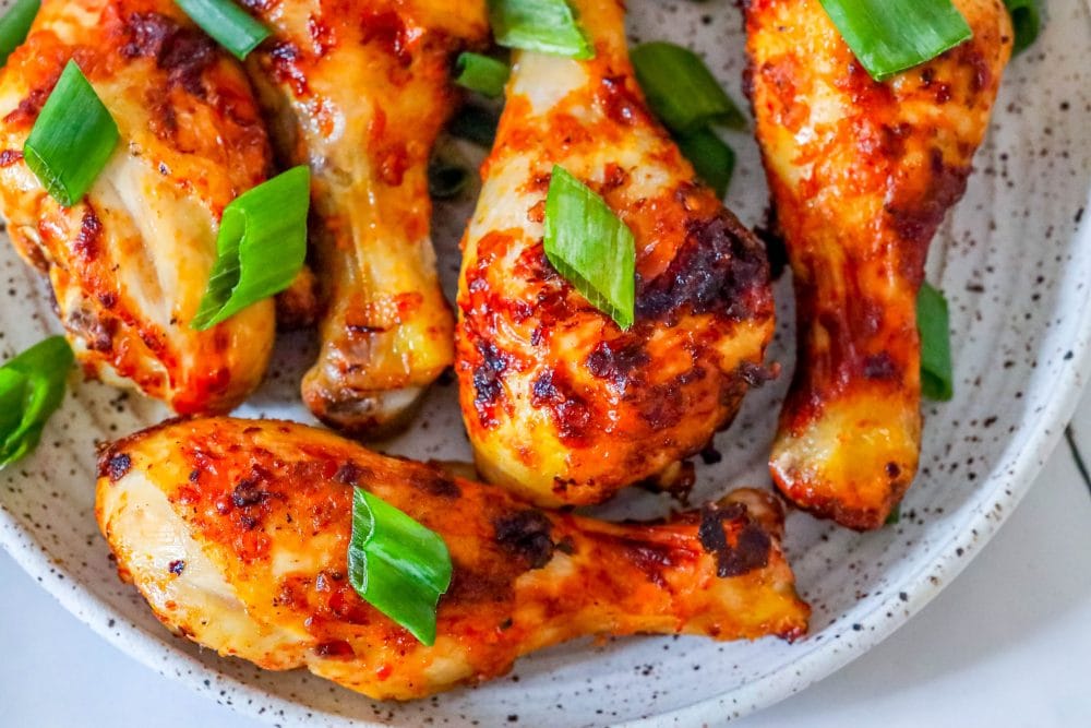 picture of spiced chicken drumsticks with green onions on it. 
