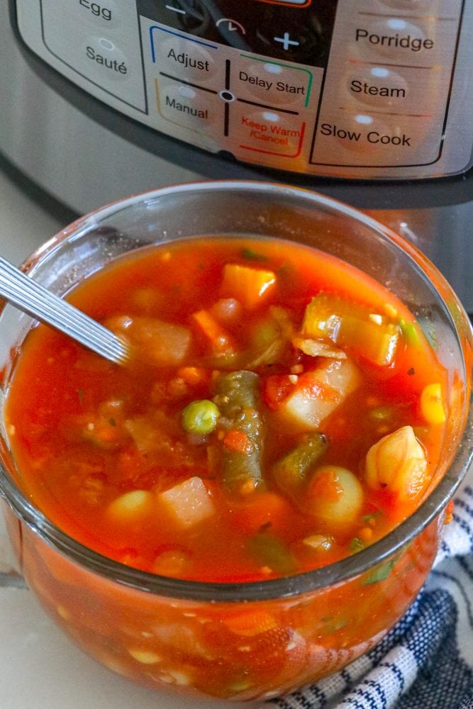 tomato and vegetable soup in a clear mug in front of an instant pot