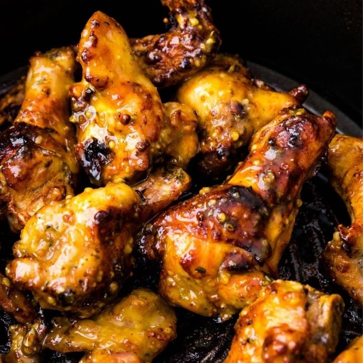 Air fryer honey mustard chicken wings in a black skillet.