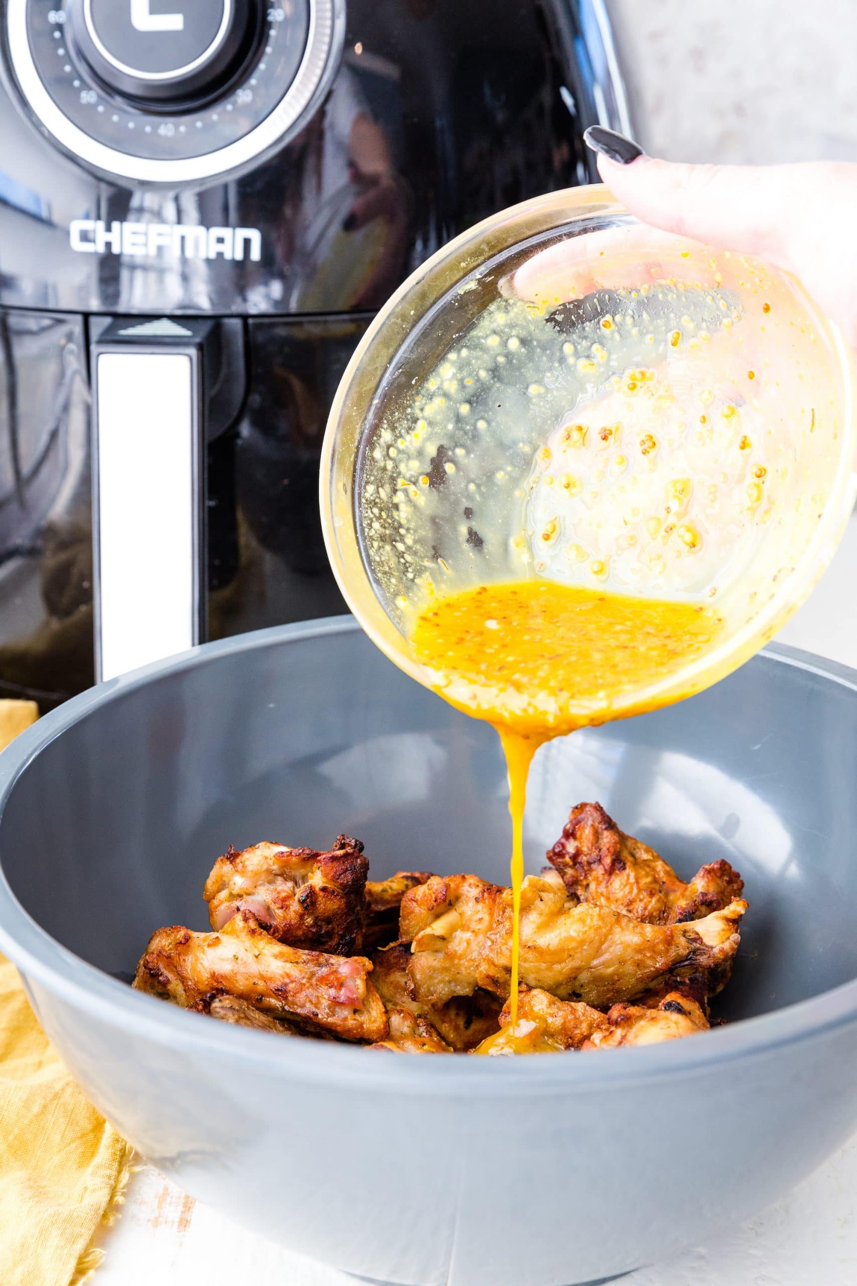 sauce being poured over wings