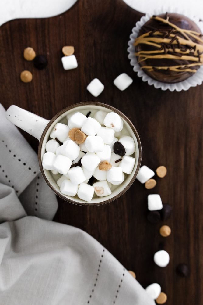 mug full of marshmallows and chocolate chips on wooden countertop