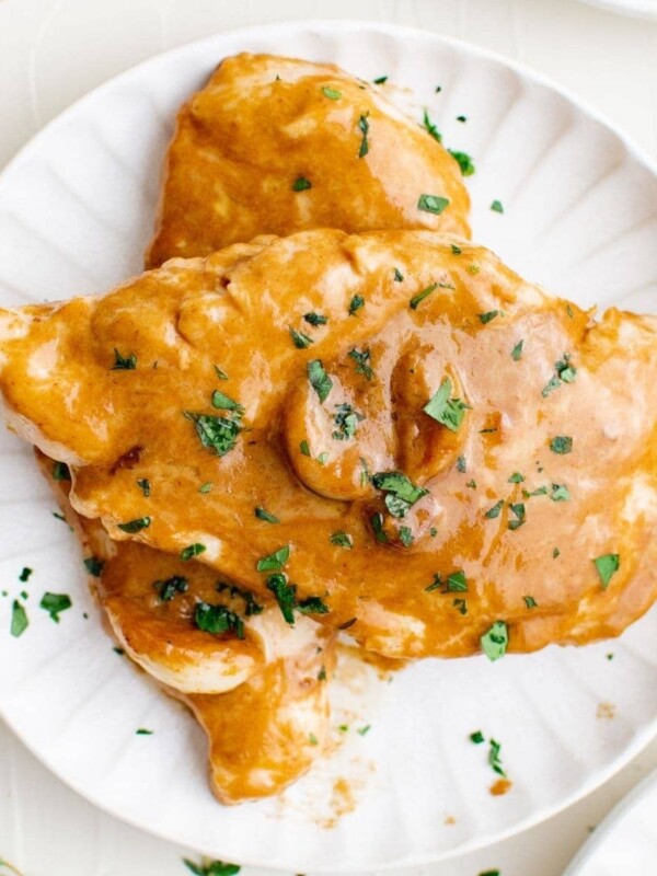 A plate with chicken covered in creamy garlic sauce.