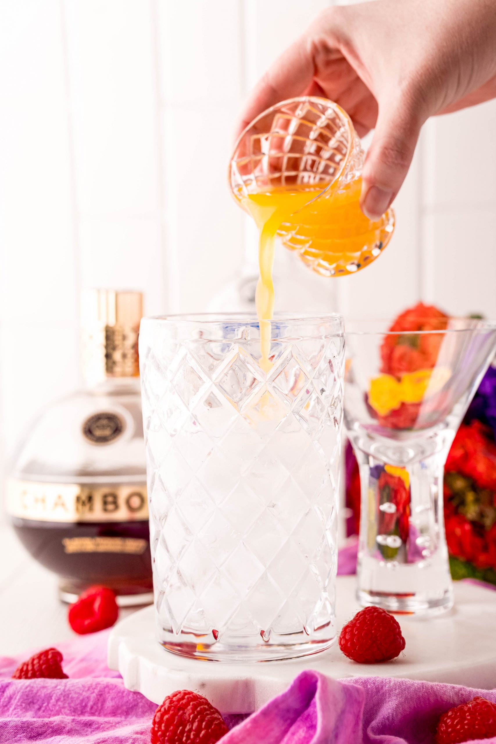 pouring orange cocktail into a cup of ice