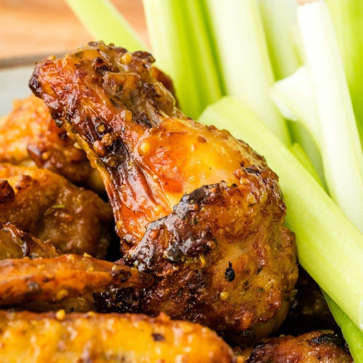 Chicken wings with honey mustard sauce served alongside celery sticks.