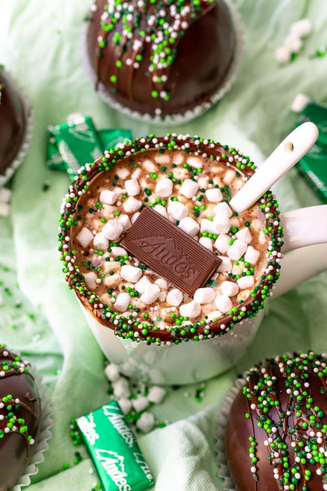 mint hot chocolate in a white mug with an Andes mint in it and one on the green base. 