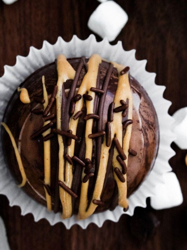 A peanut butter hot chocolate bomb-inspired chocolate cupcake with marshmallows and chocolate drizzle.