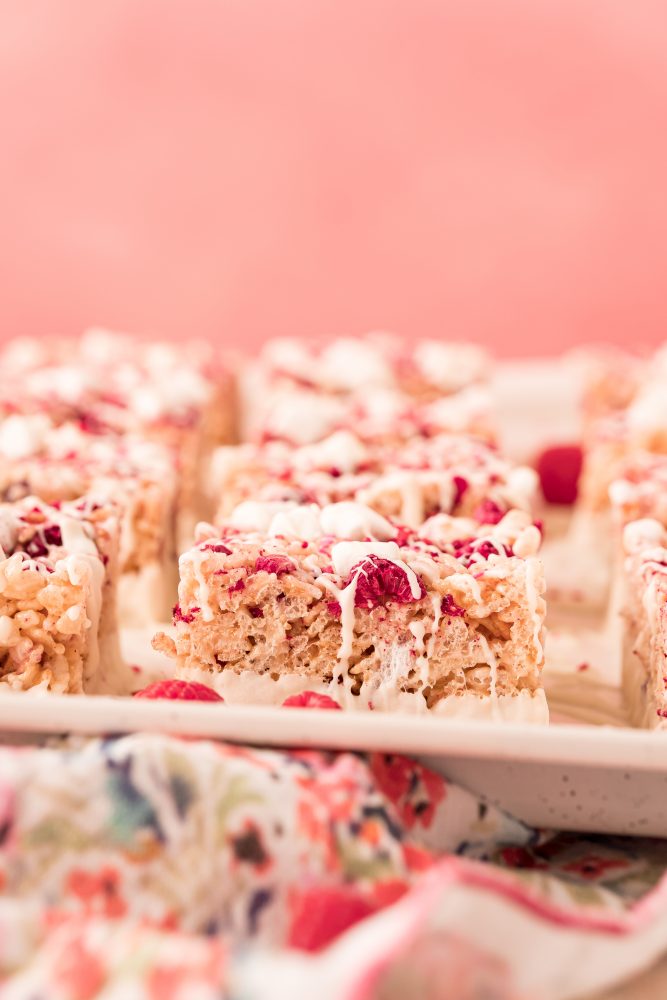 pink rice Krispie treat with marshmallows, freeze dried raspberries in it and white chocolate drizzle