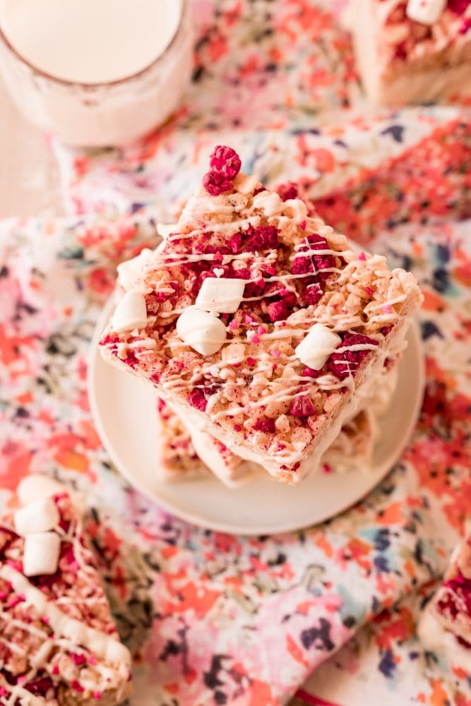 pink rice Krispie treat with marshmallows, freeze dried raspberries in it and white chocolate drizzle