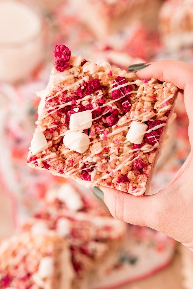 pink rice Krispie treat with marshmallows, freeze dried raspberries in it and white chocolate drizzle up close